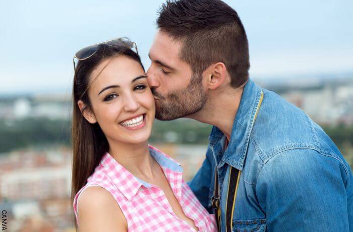 Foto de un hombre dándole un beso en la mejilla a una mujer