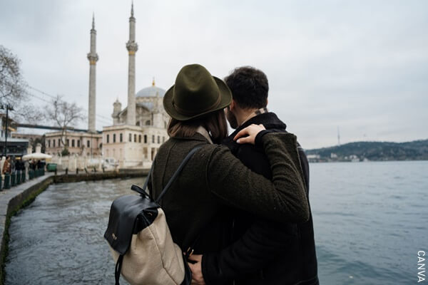 Fotografía pareja hombre y mujer abrazados mientras miran un castillo