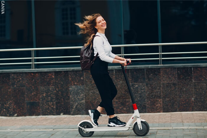 Fotografía de una mujer feliz montando una patineta electrica