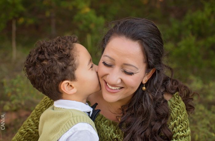 Foto de un niño dándole un beso en la mejilla a su mamá