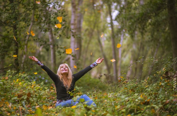 Foto de una mujer feliz sentada en medio del bosque