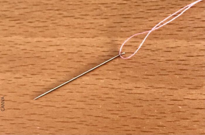 Foto de una aguja con hilo rosa