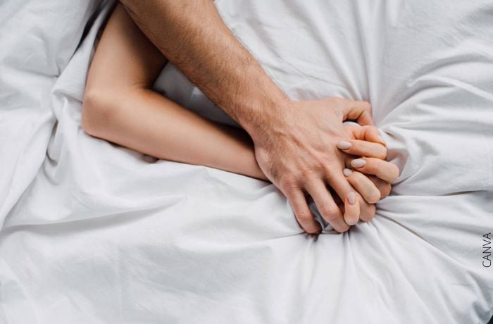 Foto de las manos agarradas de una pareja en la cama