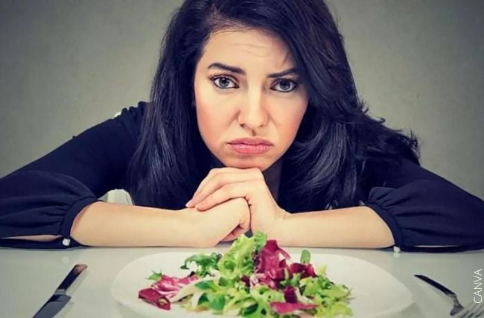 Foto de una mujer con cara de asco frente a una ensalada