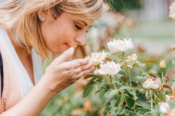 Foto de mujer oliendo flores.