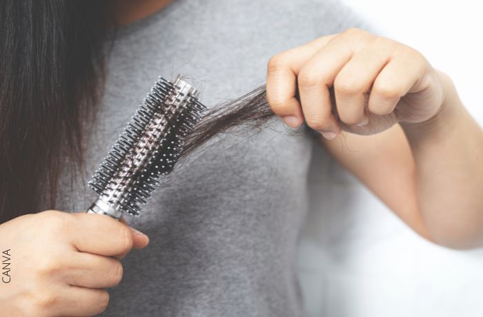 Foto de una persona sacando cabello del cepillo
