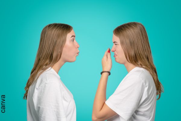 Foto de mujer soplándole a otra mujer que se tapa la nariz.