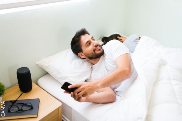 Foto de hombre en el celular mientras mujer duerme al lado.