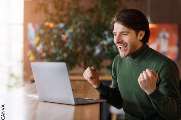 Foto de hombre feliz frente a una computadora.