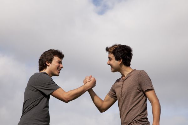 Foto de dos hombres agarrados de la mano confirmando su amistad