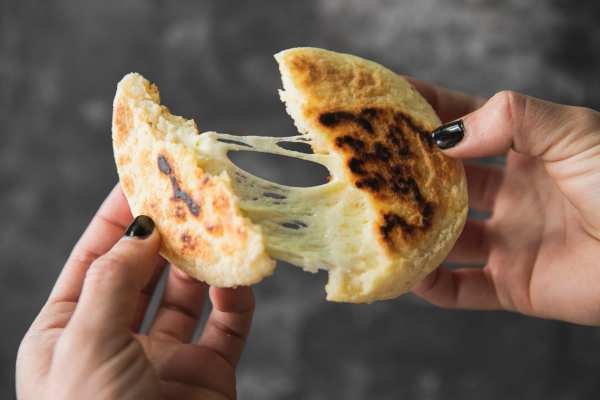 Arepa rellena de queso siendo partida a la mitad