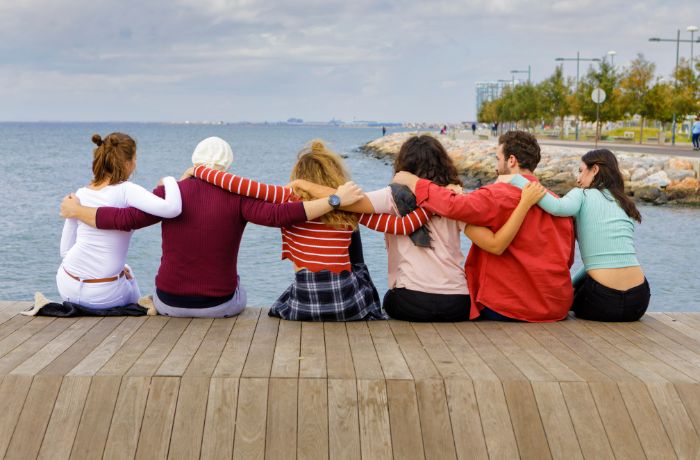 Foto de 6 personas abrazadas frente a un lago afianzando su amistad