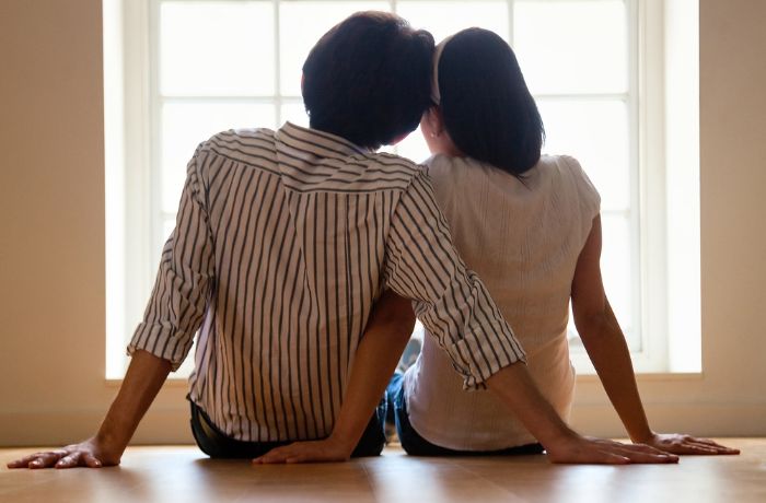 Foto de una pareja sentada con los brazos cruzados entre sí y mirando por la ventana