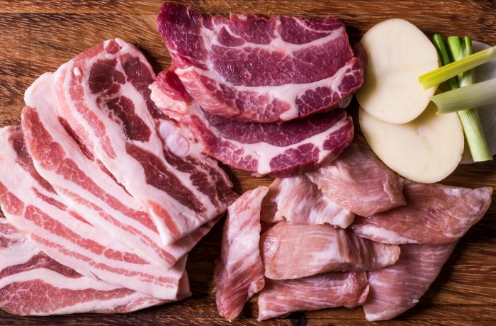 Carne sobre una mesa junto a unas papas y cebollas