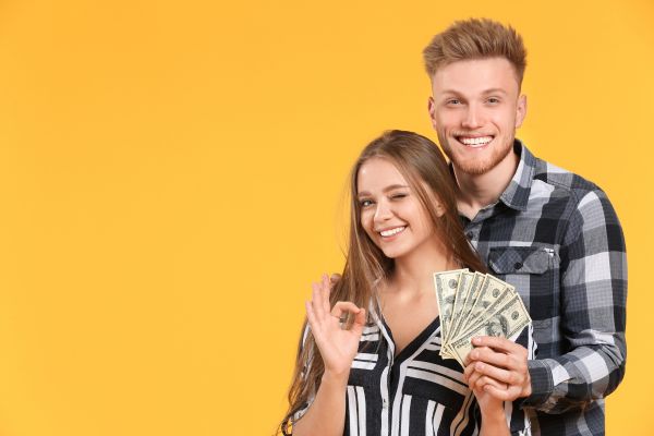 Foto de una pareja con dinero en las manos haciendo cara de felicidad