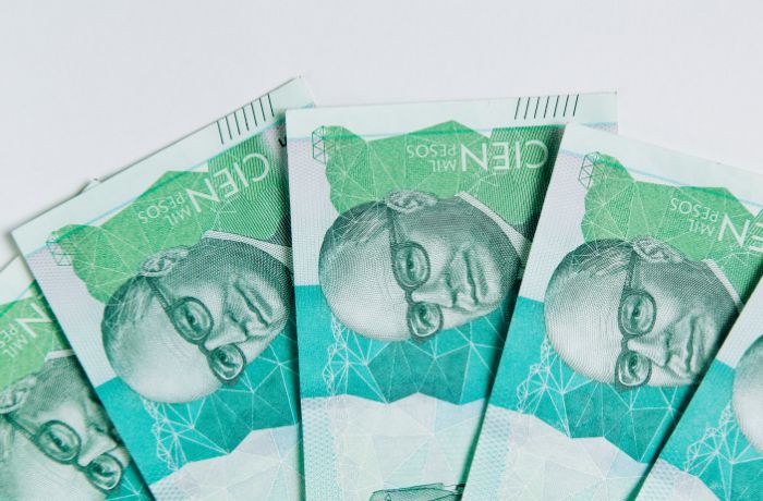 Foto de 5 billetes de 100 mil pesos colombianos sobre una mesa
