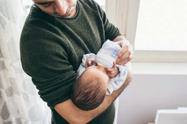 Foto de un papá dando tetero a un bebé