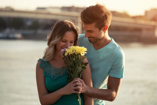 Foto de hombre regalándole flores a una mujer.