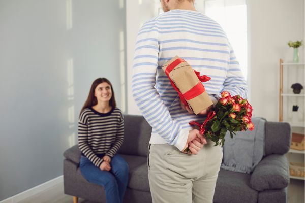 Foto de hombre regalando flores y detalle a una mujer.