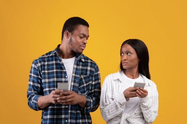 Pareja mirándose con celular en la mano.