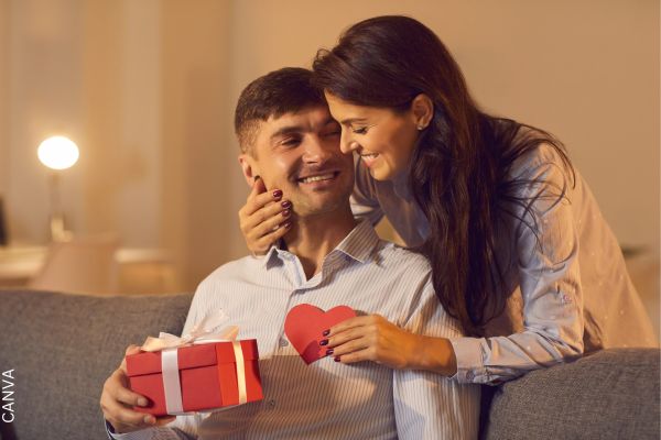 Foto de mujer dándole un regalo a un hombre.