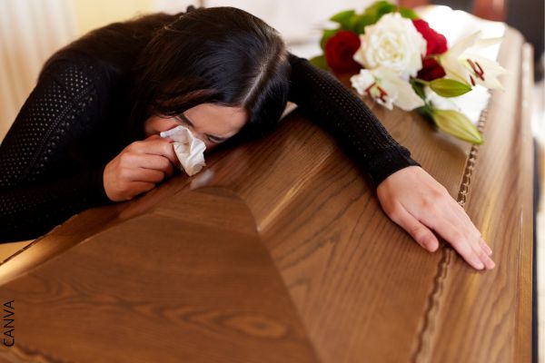 Foto de mujer llorando en un ataúd.