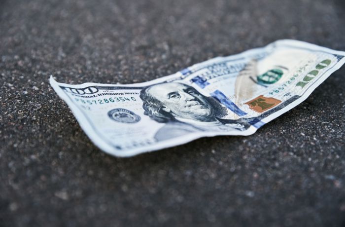 Foto de un dólar de 100 tirado en el suelo.