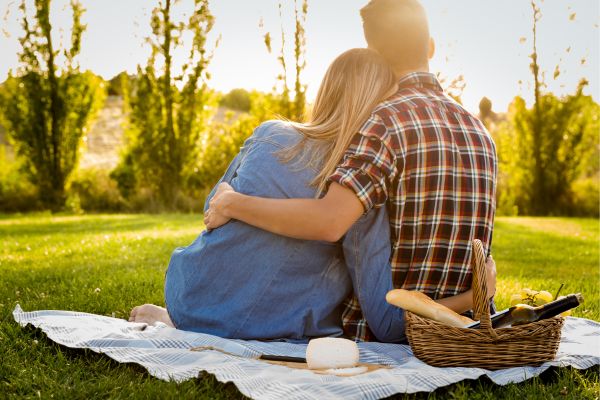 Foto de una pareja en un pícnic y mirando el atardecer.