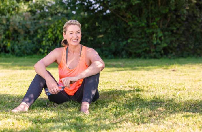 Foto de mujer sentada en un parque con ropa de hacer ejercicio