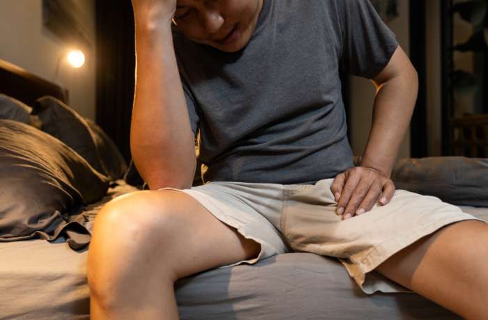 Foto de hombre sentado en la cama y enfermo