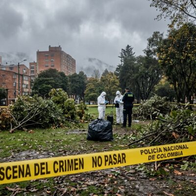 Investigadores forenses en una escena del crimen acordonada con cinta de la Policía Nacional de Colombia